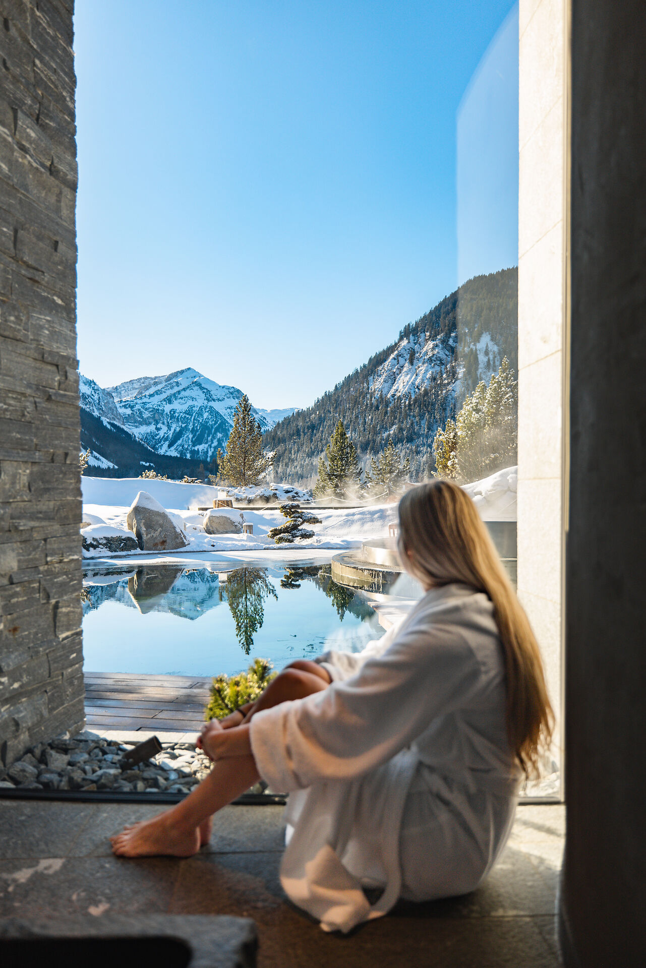 Ausblick vom Wellnessbereich auf den Quellteich und die Berge